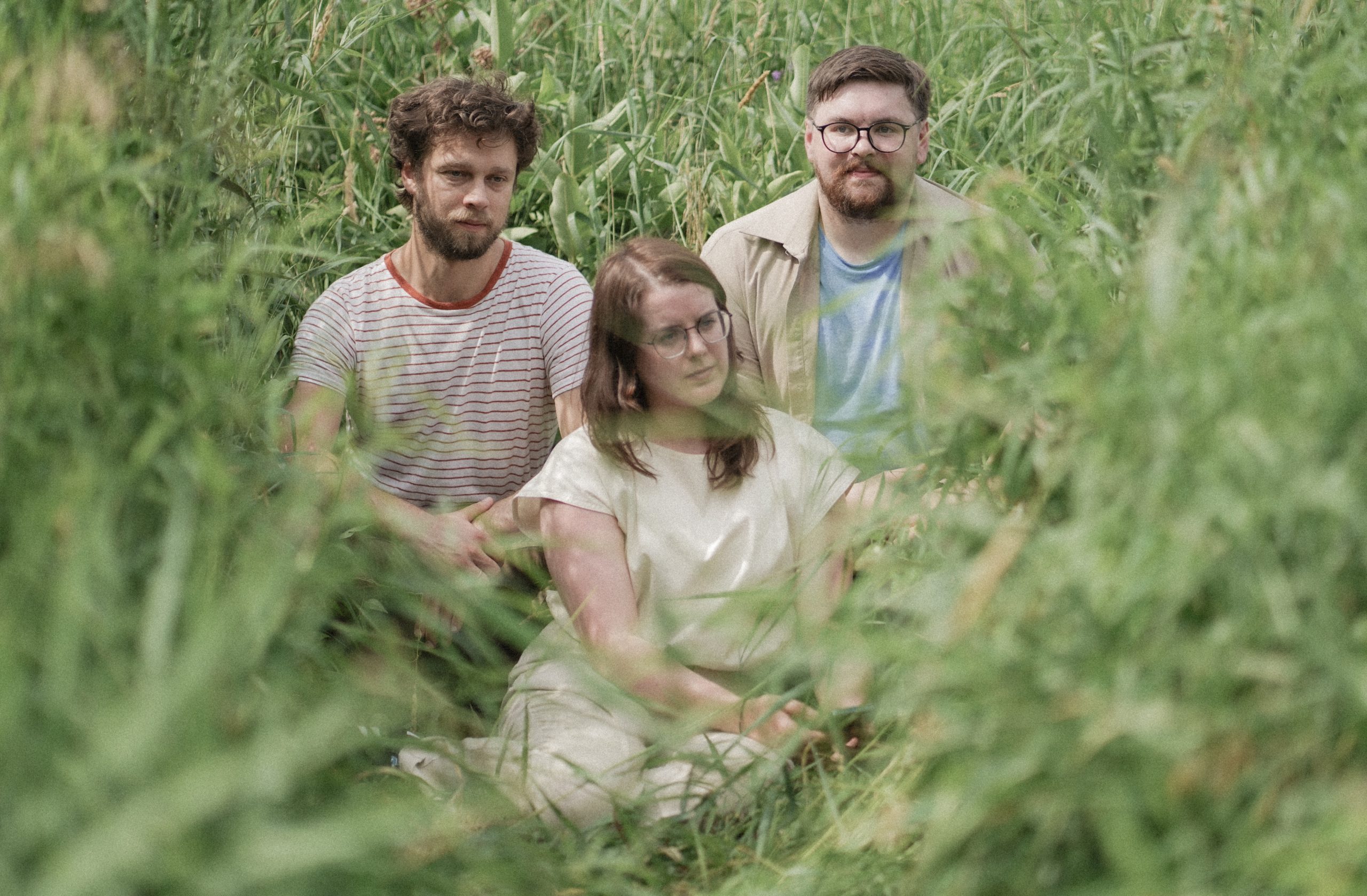 Chamber-pop trio Pallmer pose for a photo in tall grass.