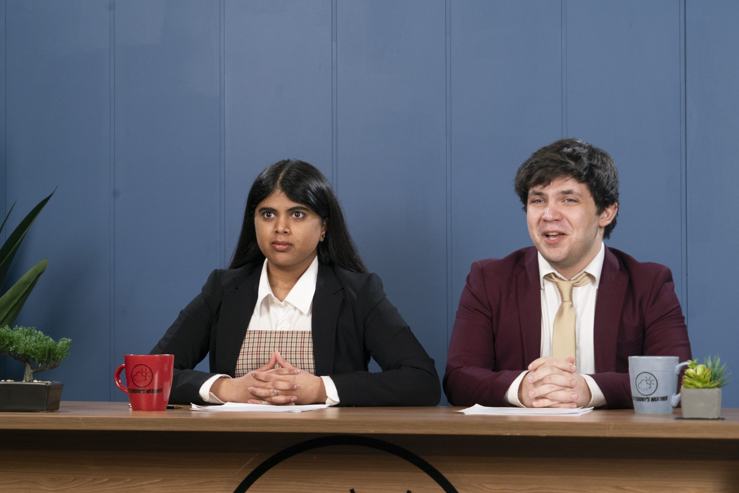 Two news anchors sitting at a desk.
