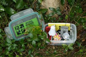 A sample small geocache, containing a pencil, a logbook for finders to sign, batteries and toys (which finders may take, leaving in exchange items they bring), and a travel bug, which may be tracked online as it moves from cache to cache across the country or around the world.