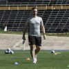 Joe Hamilton walks across a soccer field surrounded by soccer balls and cones.