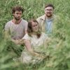 Chamber-pop trio Pallmer pose for a photo in tall grass.